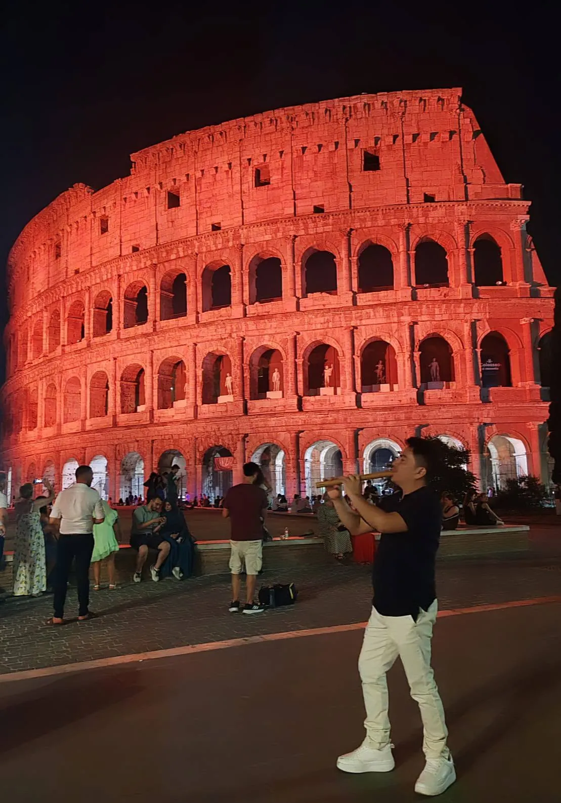 Jonathan Cachay tocando la zampoña frente al Coliseo de Roma iluminado de rojo